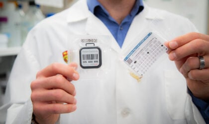 Dr. Dustin Pearson holding a radon test kit and a toenail sample collection bag (Credit: Glynnis Mutch Photography)
